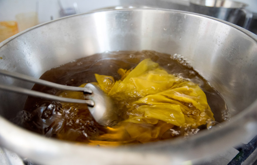 Dyeing silk satin a particular hue and shade of yellow.